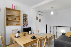 A dining area with a wooden table, chairs, a bookshelf, and a TV.