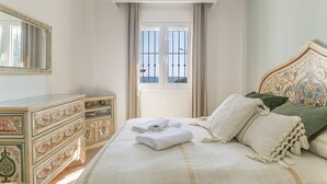 A bedroom with a bed, a dresser, a window with curtains, and a mirror. - 'Mirador De La Atalaya' Apartment with Sea View, Private Terrace, Garden & Wi-Fi (Conil de la Frontera)