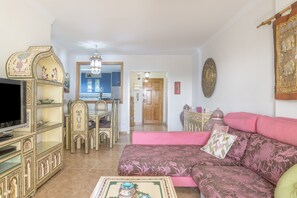 A living room with a television, sofa, and decorative furniture. - 'Mirador De La Atalaya' Apartment with Sea View, Private Terrace, Garden & Wi-Fi (Conil de la Frontera)