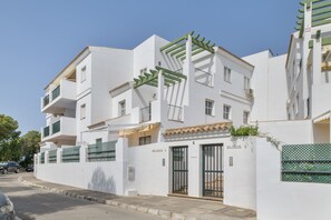 A white building with balconies, a gated entrance, and a clear sky.