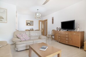 Un salon comprenant un canapé, une table basse, un téléviseur et un meuble en bois.