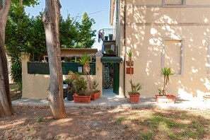 A building with a green door, potted plants, and a balcony with clothes hanging.