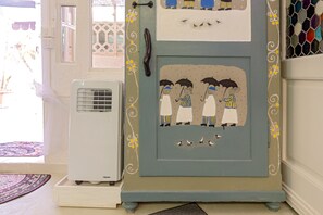 A room with a decorative door, a window, and a white air conditioning unit.