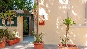 Entrada de un edificio con un letrero que dice 'STUDIO SCULPTURA', plantas en macetas y una puerta de acceso.