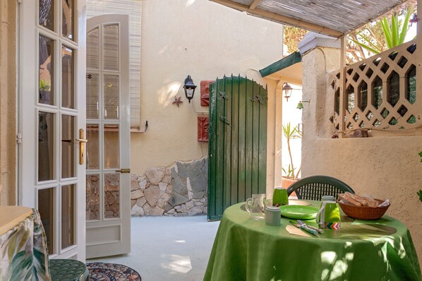 A patio with a table set for dining, a green door, and a stone wall.