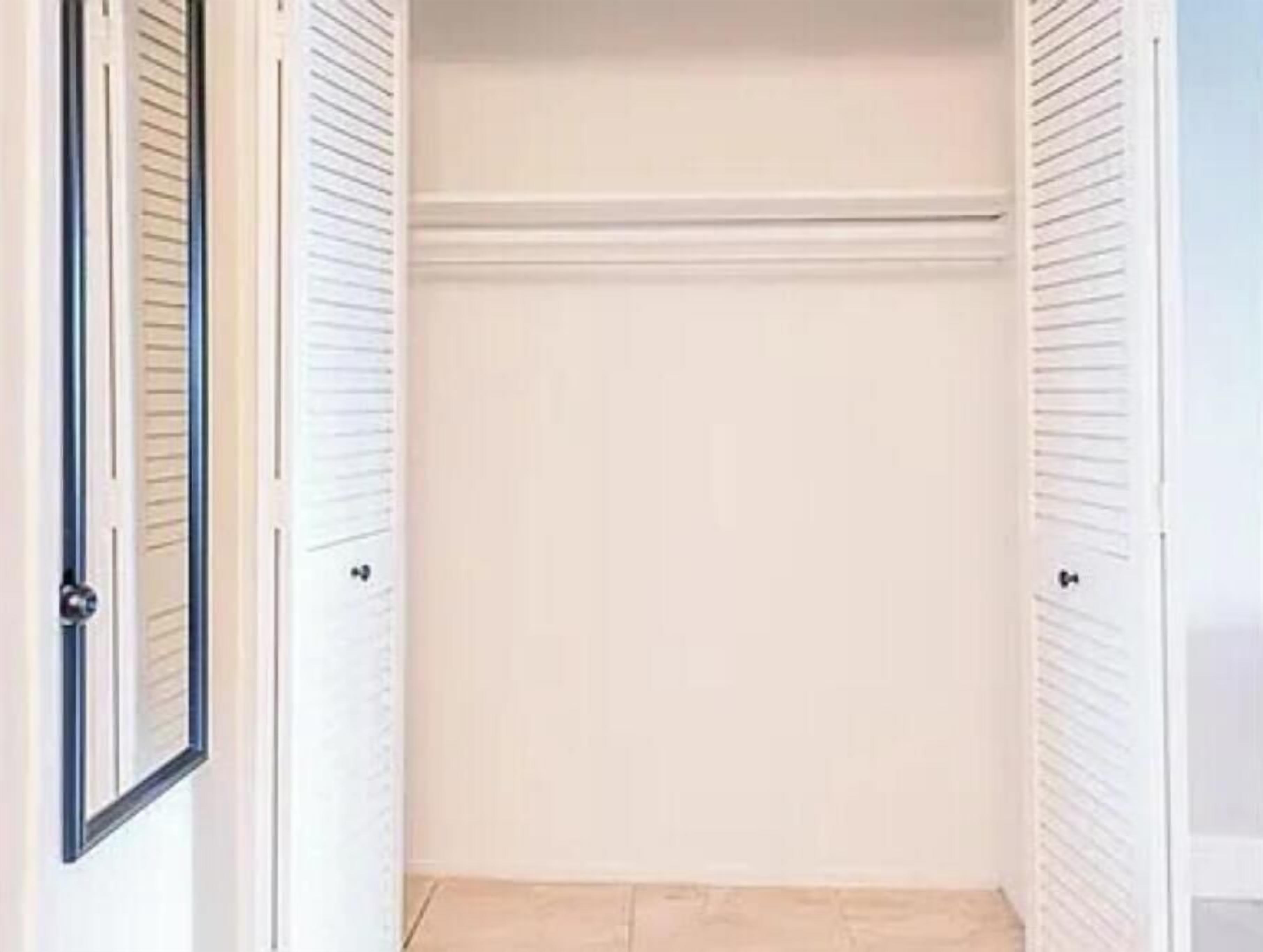 Un vestidor con puertas correderas y piso de baldosas.