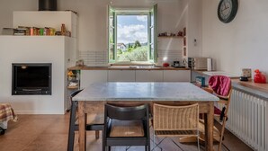 A kitchen with a large window, a built-in TV, and a dining area with chairs. - Holiday Home 'Dulù - Luminoso Spazio' with Shared Garden, Balcony and Wi-Fi (Capannori)