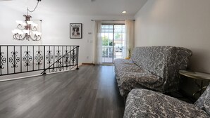 Ein geräumiges Wohnzimmer mit einer gemusterten Couch, einer Kristallleuchter und Blick ins Freie.