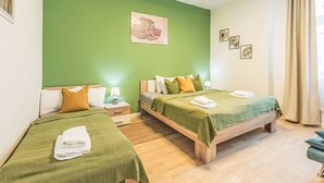 A hotel room with two beds, green walls, wooden furniture, and artwork. - Washington by Interhome (Prague centre)