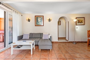 A living room with a grey sofa, white coffee table, and tiled floor. - Apartment 'Con Encanto' with Sea Views, Wi-Fi and Air Conditioning (Las Lagunas de Mijas)