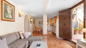 Una sala de estar con un sofá gris, una mesa de centro blanca y un comedor con sillas de madera.