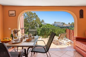 Un balcone con tavolo apparecchiato per mangiare, sedie, un divano e vista sulla città.