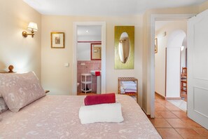 Una camera da letto con un letto, un comodino, uno specchio e un bagno visibile attraverso una porta aperta.