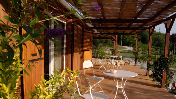 A wooden deck with a pergola, two white metal chairs, and a small round table. - "Cytise" Room with Private Terrace, Shared Garden, Wi-Fi, E-Bike Friendly (L'Épine)