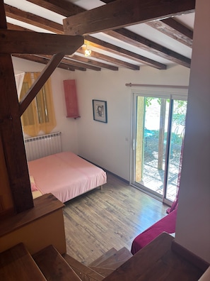 Ein Schlafzimmer mit Bett, Fenster, Tür und Treppe.