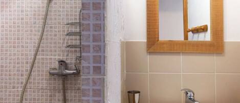 Une salle de bain avec une douche, un lavabo et un miroir.