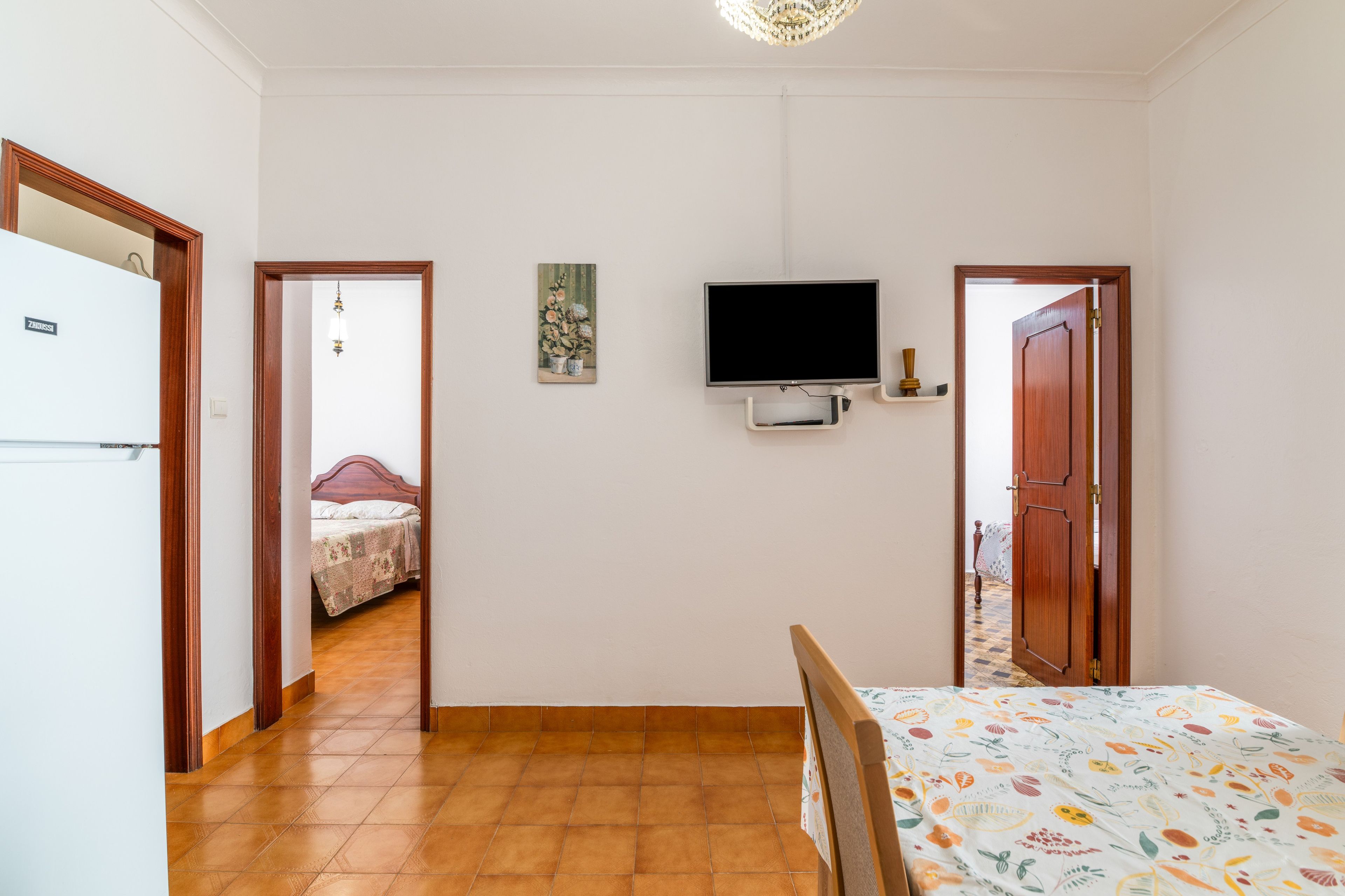 A room with a bed, a television mounted on the wall, and a door leading to another room.