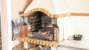 Un four en briques avec une grille métallique et une dalle de pierre.