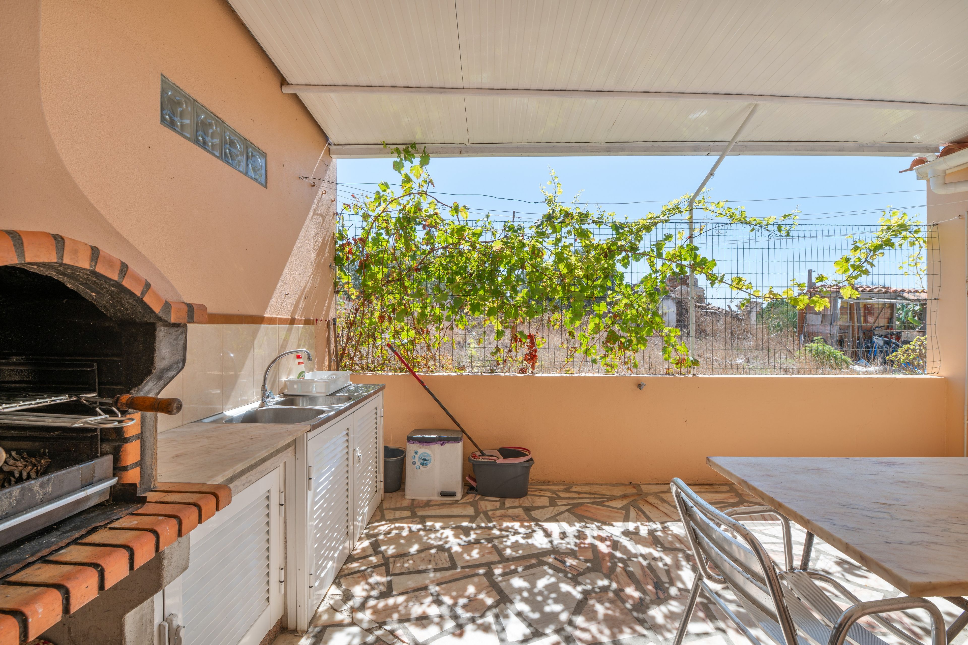 A kitchen with a brick oven, sink, and a window overlooking a garden.