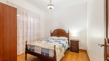 Een slaapkamer met een houten bed, een nachtkastje, een lamp en een kroonluchter.