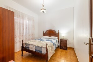 A bedroom with a wooden bed, a nightstand, a lamp, and a chandelier. - Holiday Home 'Encanto' with Private Terrace and Wi-Fi (Santo André)
