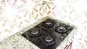 Une cuisine équipée de quatre brûleurs à gaz, d’une hotte en acier inoxydable et d’un crédence décorée.