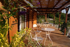 A wooden deck with a pergola, two white metal chairs, and a small round table. - Room "Tilleul" with Private Terrace, Shared Garden, Wi-Fi, and E-Bike Charging (Unknown)