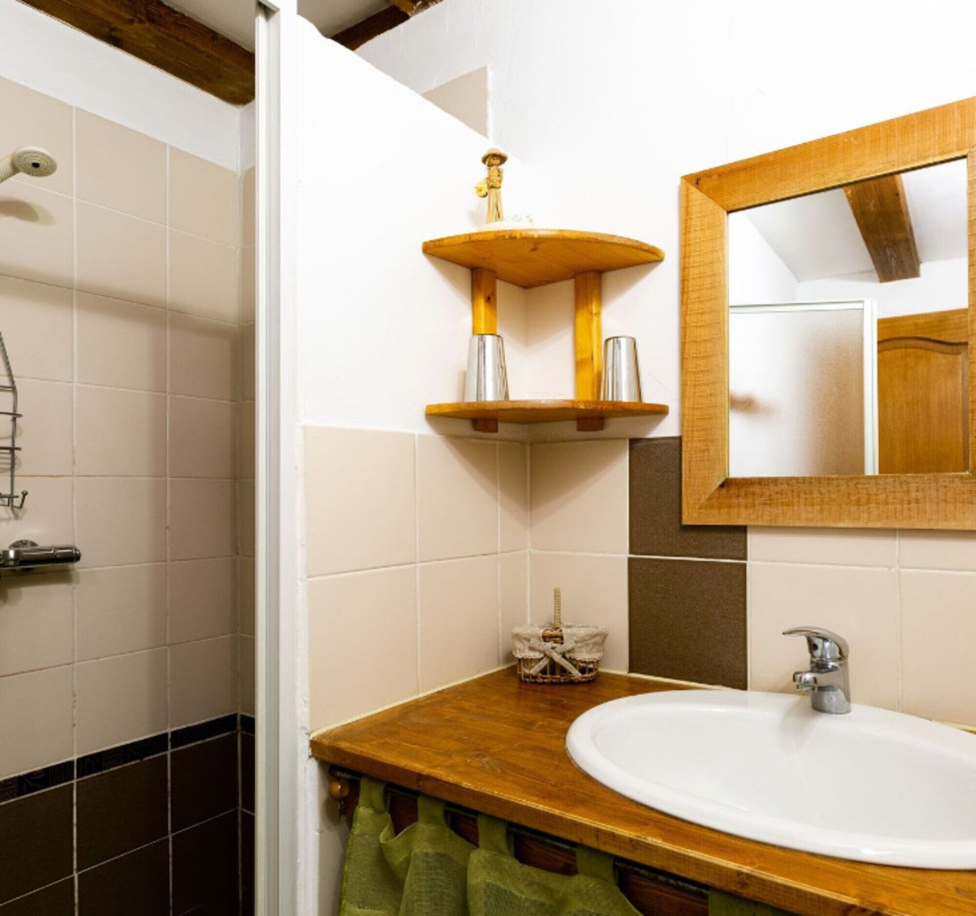 A bathroom with a wooden vanity, a sink, a mirror, and a shower area.