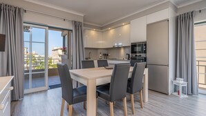 A modern kitchen with a dining area, large windows, and a view of the city.