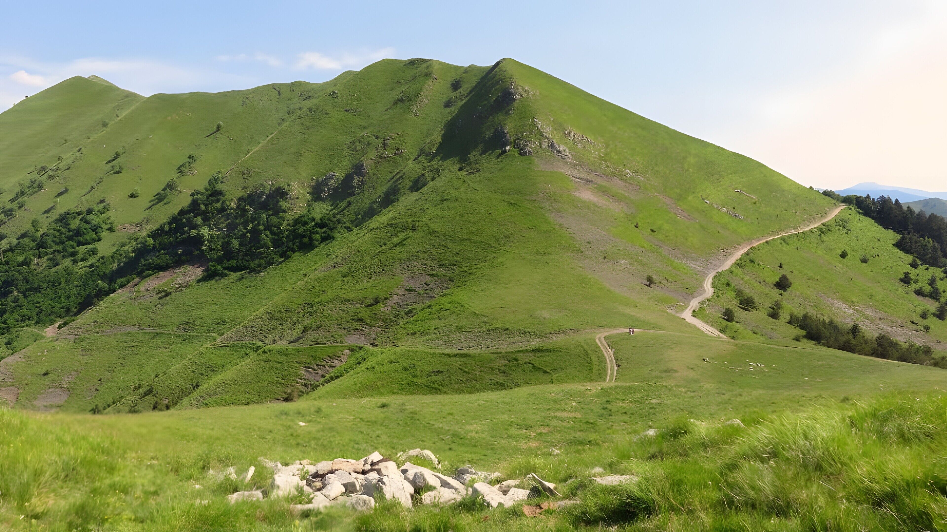 Paesaggio montuoso con un sentiero sterrato che sale sulla collina.