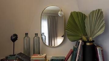 Une pièce avec un miroir, des livres, des vases décoratifs et une plante en pot.