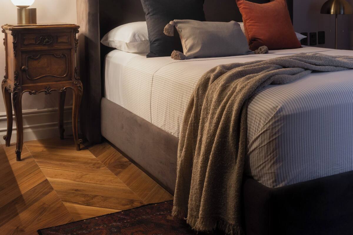 Ein Schlafzimmer mit einem großen Bett, einem Nachttisch mit Lampe und einem gemusterten Teppich.