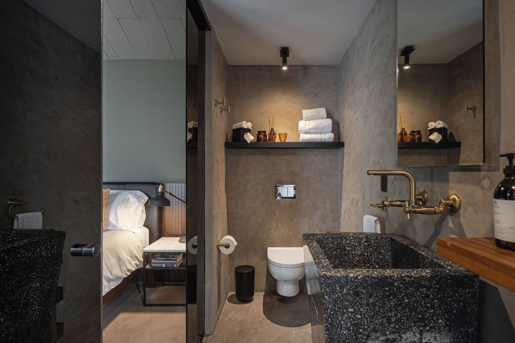 A modern bathroom with a large mirror, a freestanding bathtub, and a toilet.