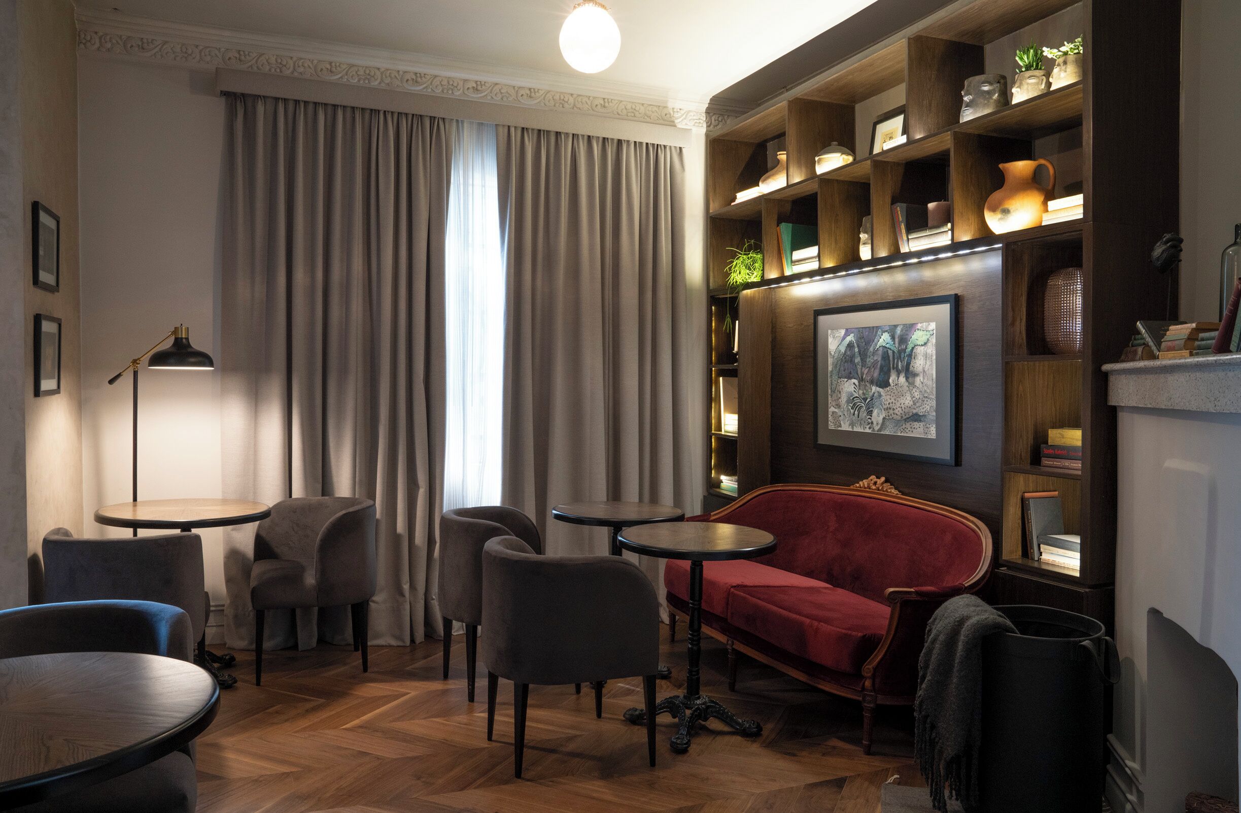 A cozy living area with a red sofa, two armchairs, a coffee table, and a bookshelf with decorative items.