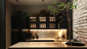 A modern kitchen with a wooden countertop, a built-in oven, and a brick wall.