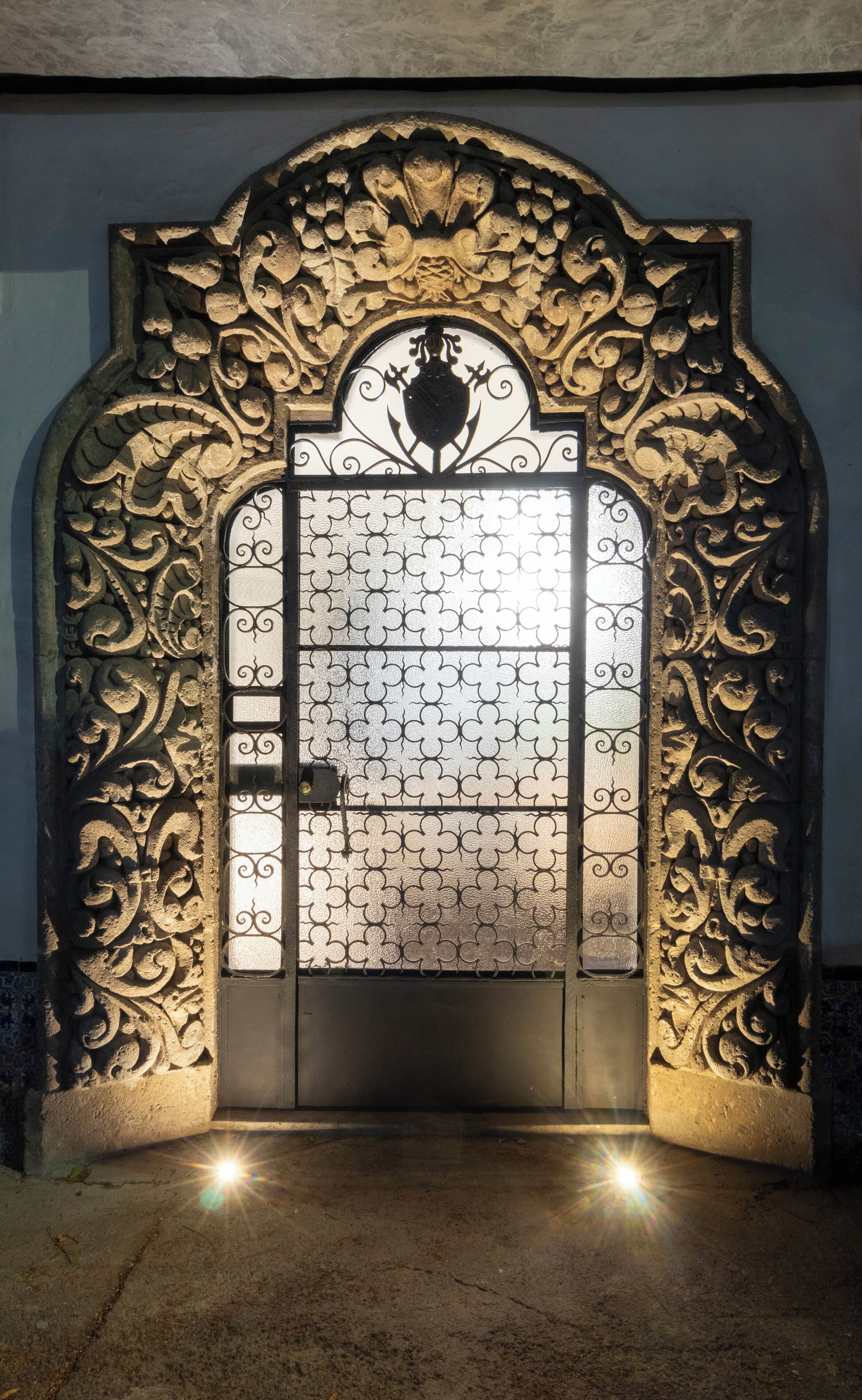 Una porta metàl·lica ornamentada amb dissenys complexos i un emblema al centre.