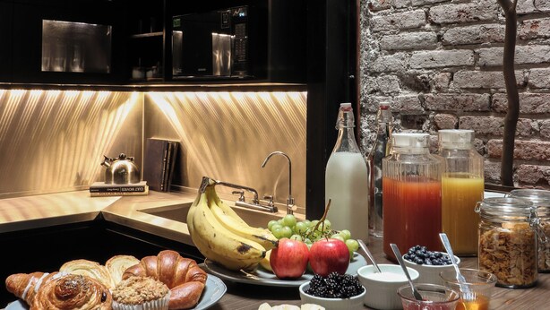 A breakfast buffet with various fruits, pastries, and beverages.