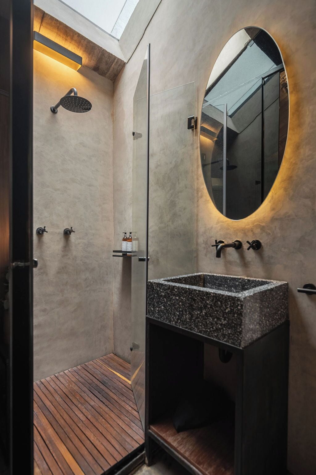 A modern bathroom with a freestanding shower, a large mirror, and a wooden floor.