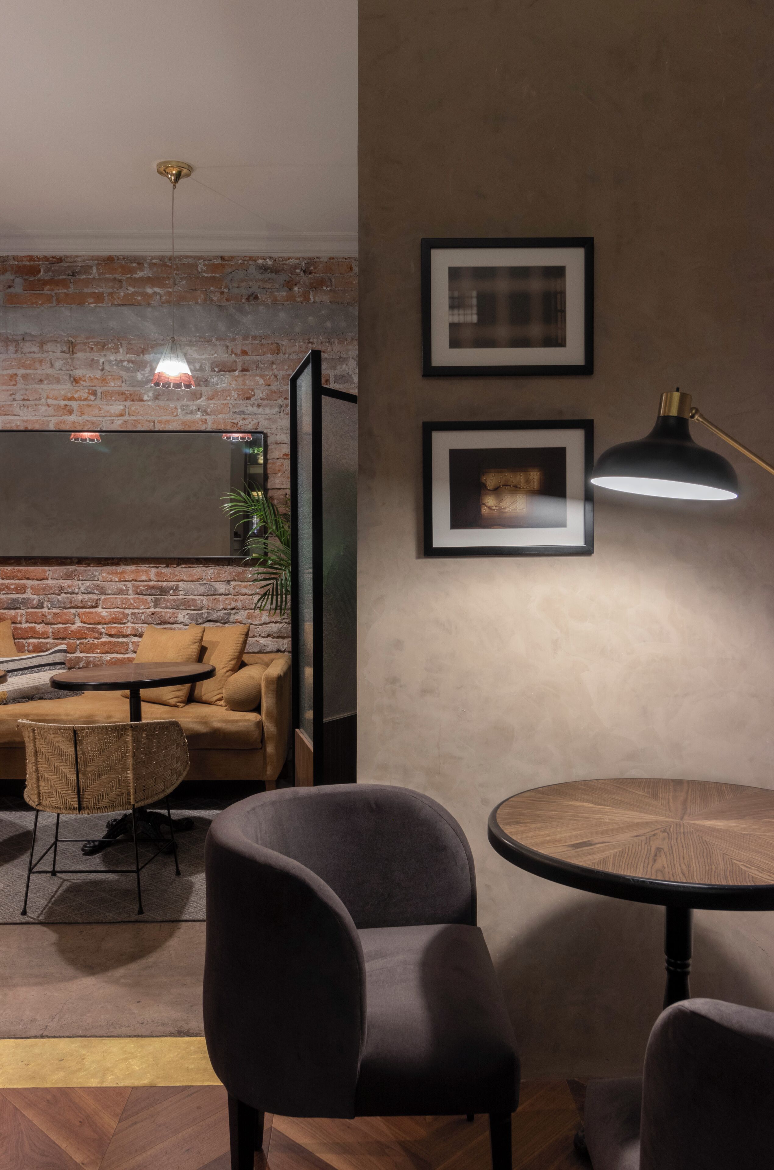 A modern living room with a brick wall, a sofa, a round table, and two framed pictures.