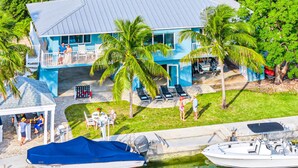 A two-story house with a blue exterior, a covered patio, and a boat dock. - Waterfront / Ocean Access Canal / Kamp Key / Homes (Islamorada)