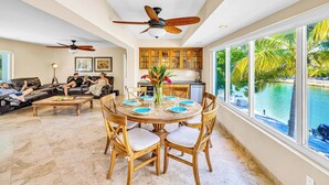 A spacious living area with a dining table, chairs, ceiling fans, and a view of a swimming pool. - Waterfront / Ocean Access Canal / Kamp Key / Homes (Islamorada)