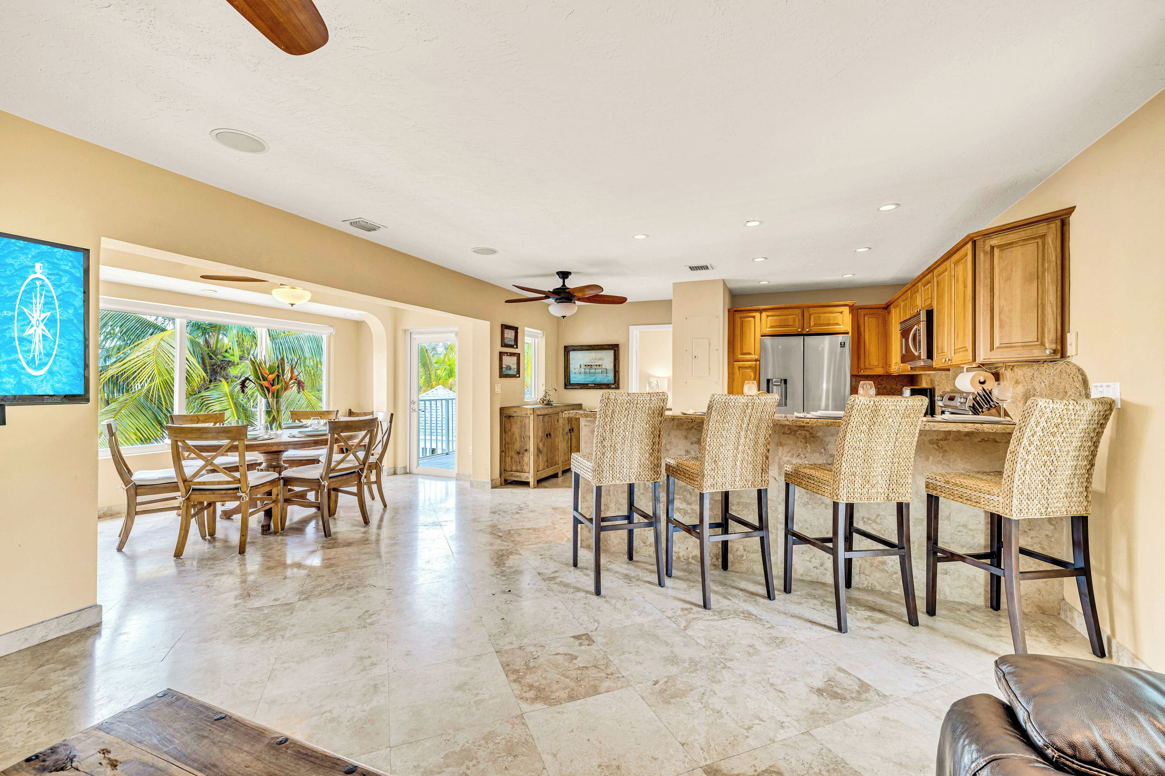 A spacious kitchen with wooden cabinets, a refrigerator, and a dining area with wicker chairs and a table.