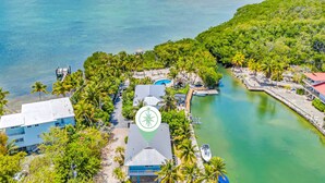 An aerial view of a coastal resort with a dock, a swimming pool, and lush greenery. - Waterfront / Ocean Access Canal / Kamp Key / Homes (Islamorada)