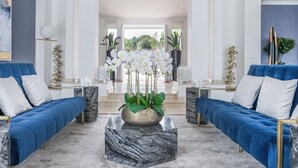 Un salon moderne avec deux canapés bleus, une table basse en marbre et des orchidées blanches.