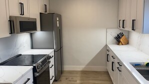 A modern kitchen with white cabinetry, a stainless steel refrigerator, a microwave, an oven, and a sink. - Dive In! The Poolside Escape with a Hot Tub, Grill, Game Room & Good Times. (Lewisville)