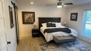 A bedroom with a bed, nightstands, a ceiling fan, and a window with blinds. - Dive In! The Poolside Escape with a Hot Tub, Grill, Game Room & Good Times. (Lewisville)