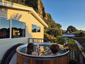 Uma banheira de hidromassagem numa varanda com vista para uma montanha e um edifício.