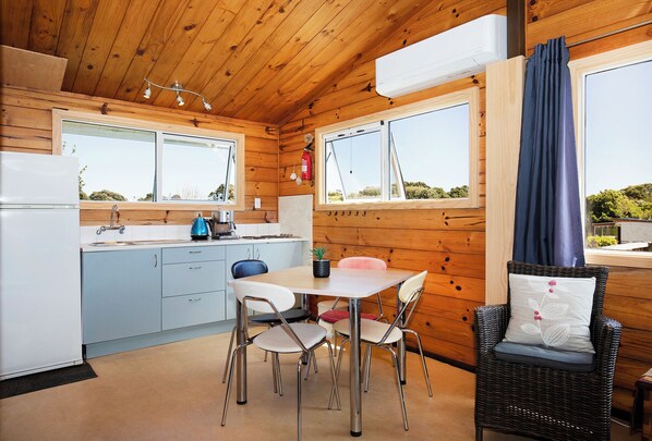Cocina compacta con comedor, paredes de madera y vistas al exterior.