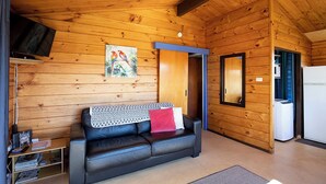 Een gezellig cabin interieur met een leren bank, houten wanden, een wandgemonteerde televisie en een schilderij.
