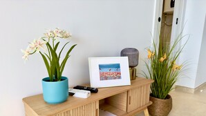 Une console en bois sur laquelle sont posés un cadre avec une photo, une télécommande et un pot de fleurs.